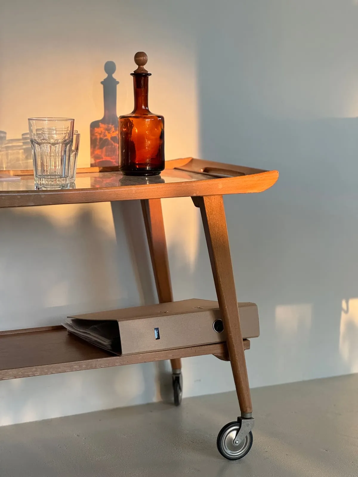 A wooden bar cart with glasses and a carafe in the morning light