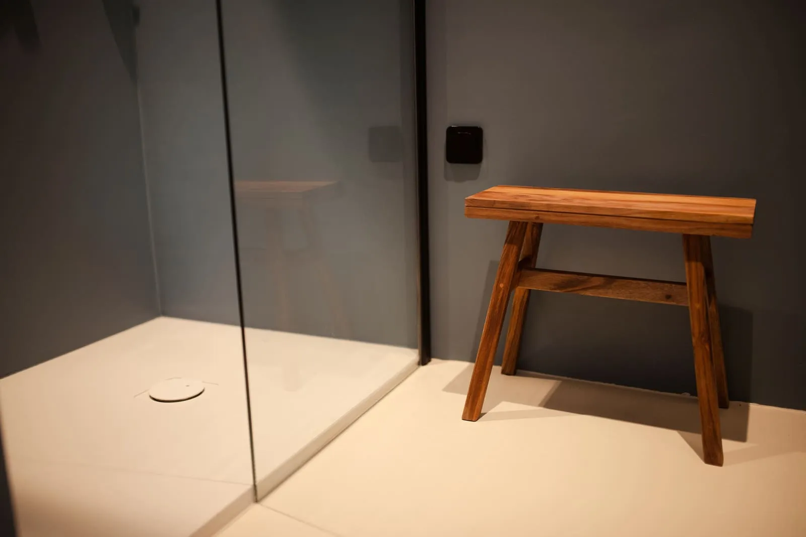 A shower with a glass enclosure and a wooden stool
