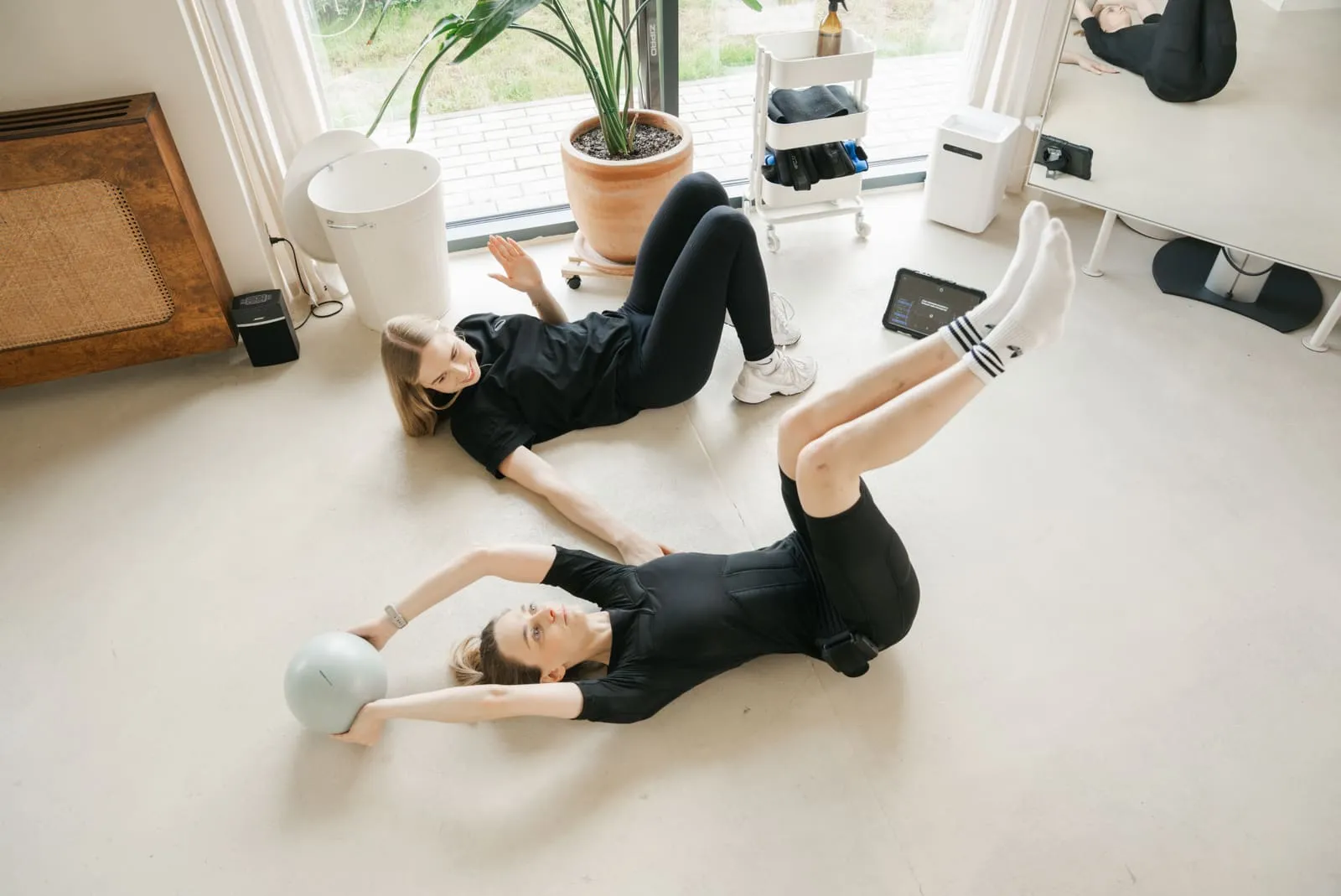 A mat exercise with a small ball, the coach spotting the client lying down