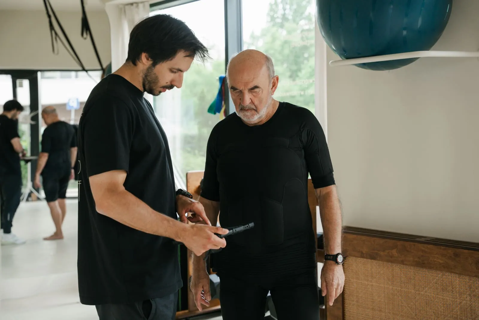 A coach setting the EMS device parameters before an older client's session