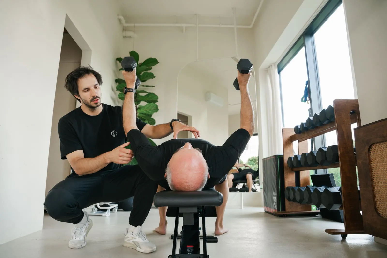 A dumbbell press on the bench with the coach spotting