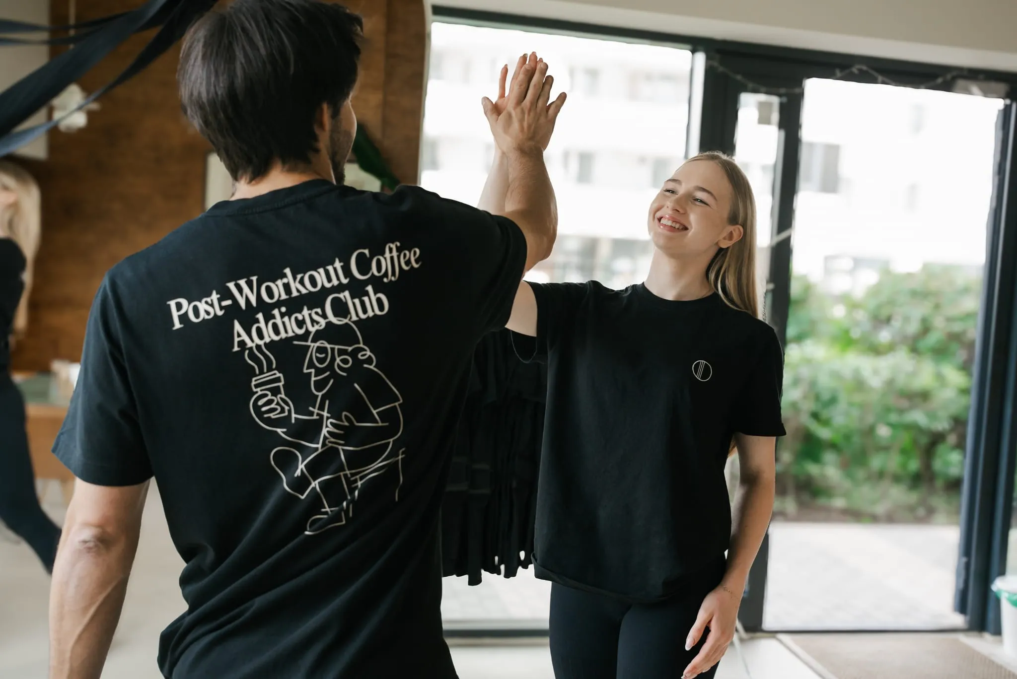 Trener i klientka w T-shirtach WORK IT przybijają piątkę po treningu