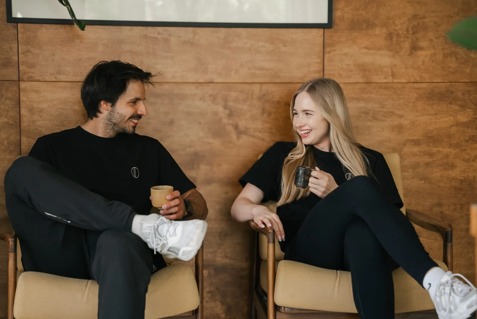 A coach and a client talking over coffee in the studio armchairs