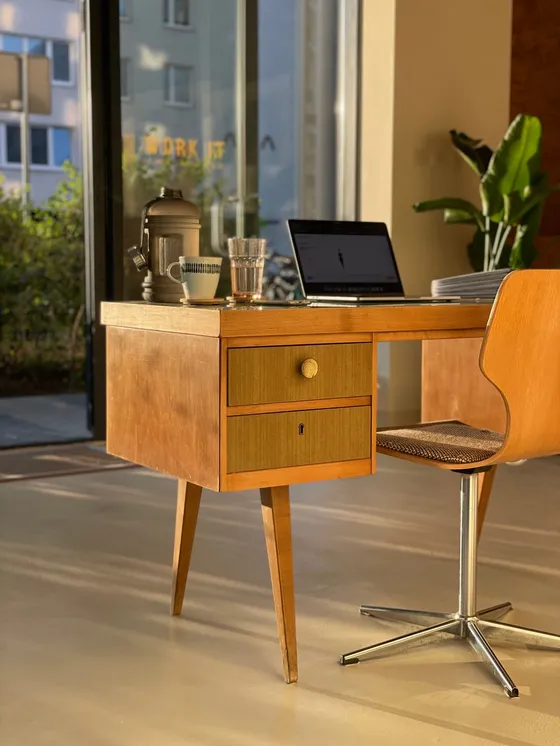 A desk with a laptop in golden light by the studio window